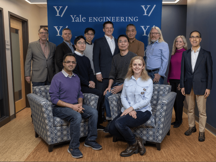 A group of smiling people in front of a Yale Engineering banner
