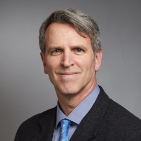 Smiling person in tweed jacket and tie