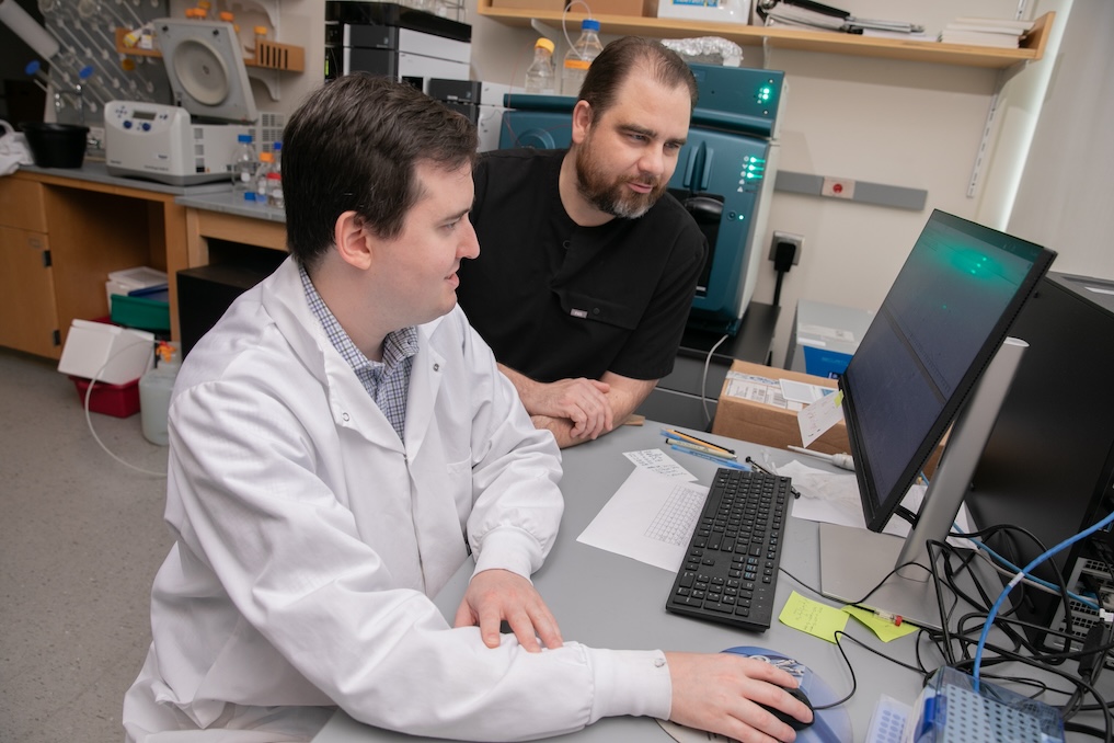 Two scientists look at a computer screen