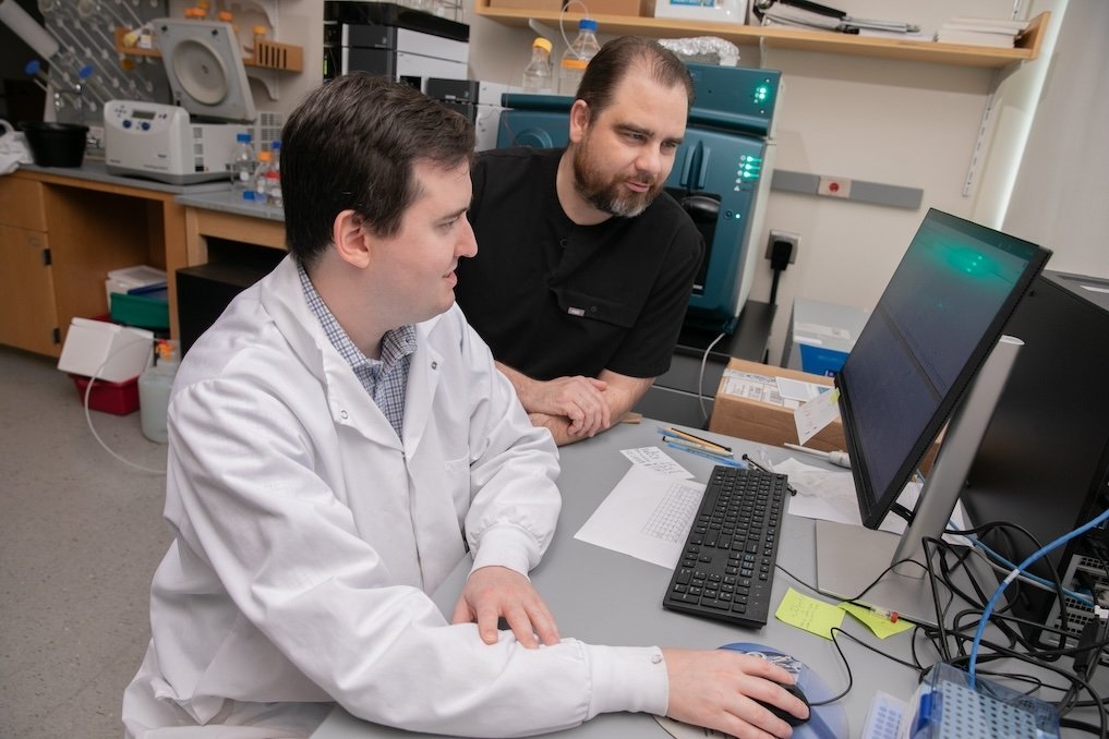 Two scientists look at a computer screen