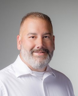 Smiling light-skinned man with short silver beard