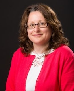 Smiling person with brown hair and glasses