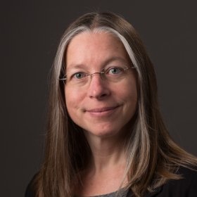 Smiling person with brown hair and glasses