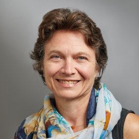 Person with short brown hair and neck scarf