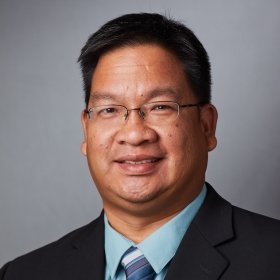 Person smiling in glasses, suit jacket, and tie