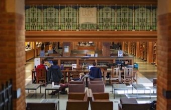 Students work at desks and sprawl in a chair in Bass library