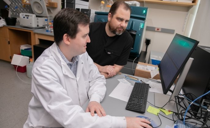 Two scientists look at a computer screen